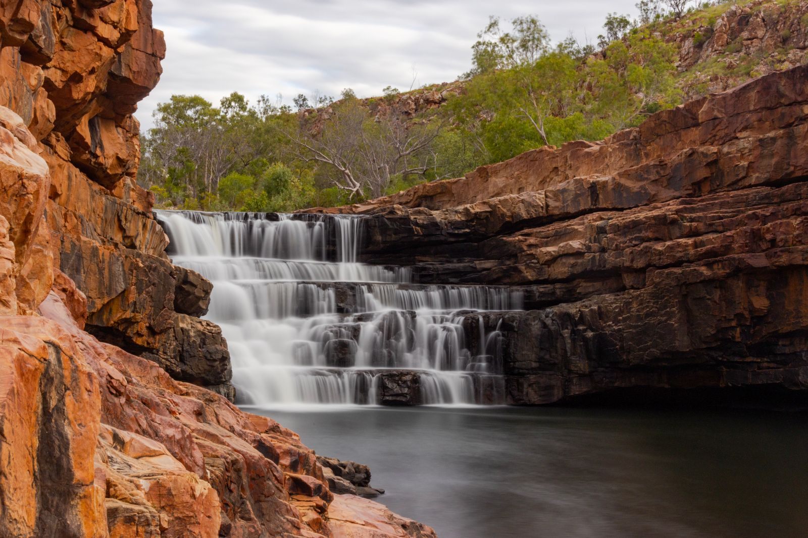 Waterfall stepping down red rock in Western Australia, the rugged scenery of small ship cruising in Australia